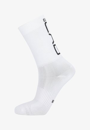 Chaussette de sport blanche avec une texture côtelée, un talon renforcé et un logo noir sur le dessus.