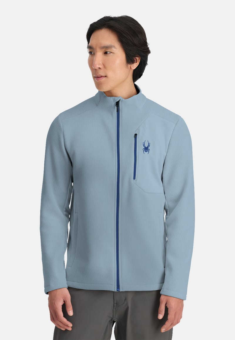 Lichtblauwe zip-up jas van gestructureerde stof. Heeft een blauwe rits en een spinlogo-patch op de borstzak.