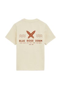 T-shirt z bawełny w kolorze kremowym, z krótkimi rękawami. Z tyłu znajduje się brązowy napis graficzny oraz wzór deski surfingowej, oznaczony jako "BLUE RIDGE DENIM".