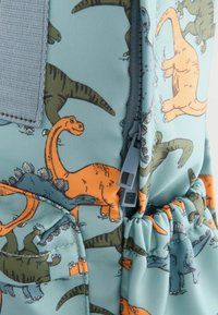 Ryggsäck i dinosauriemönster med ljusblå bakgrund, orange och gröna dinosaurier samt en grå dragkedjedetalj.