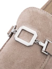Beige suède loafer met zilverkleurige metalen rechthoekige gesp en stangdetail op het bovenste deel van de schoen.