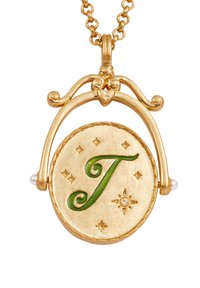 Goldanhänger mit einem grünen Buchstaben "T", umgeben von kleinen Sternen und einem dekorativen Bogen, mit jeweils zwei Perlen an beiden Seiten.