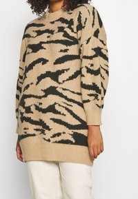 Suéter beige con patrón de rayas de tigre negras, cuello redondo, mangas largas y puños y dobladillo acanalados; hecho de material de punto suave.