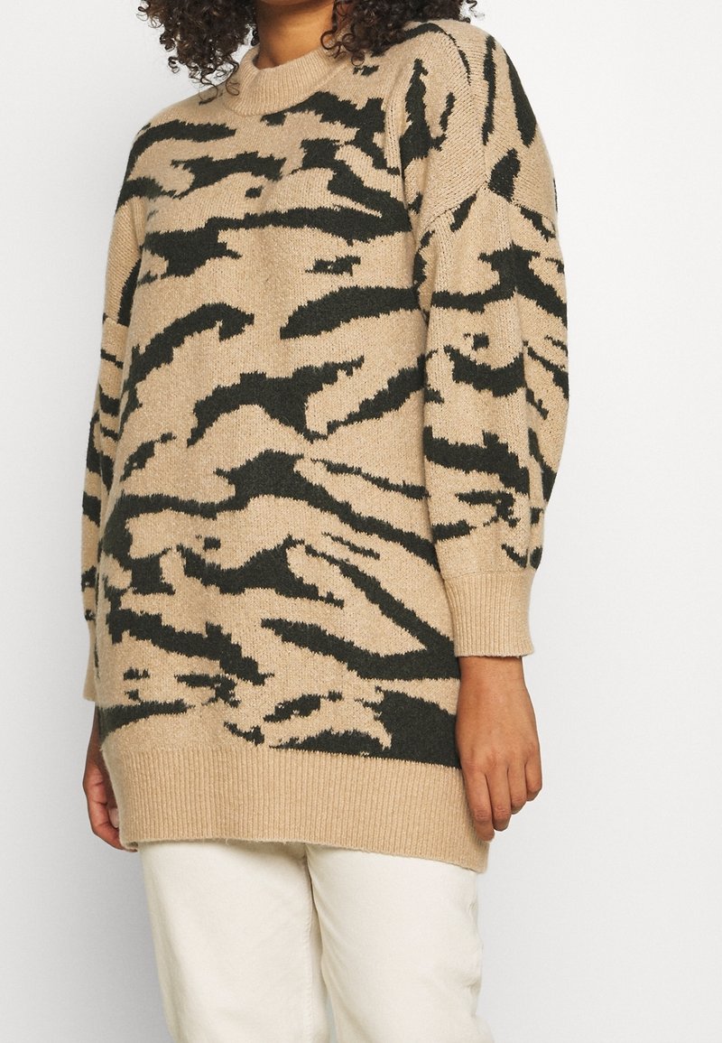 Suéter beige con patrón de rayas de tigre negras, cuello redondo, mangas largas y puños y dobladillo acanalados; hecho de material de punto suave.