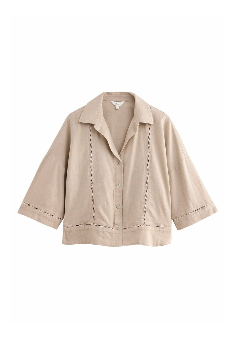 Chemise beige à boutons avec col, manches courtes larges et accents en crochet sur le devant et à l'ourlet. Fabriquée en tissu léger.