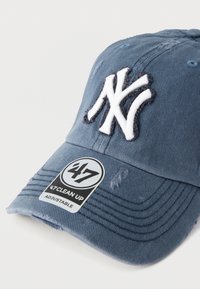 Μπλε βαμβακερό καπέλο μπέιζμπολ με λευκό κεντημένο λογότυπο NY, ρυθμιζόμενο λουράκι και φθαρμένες λεπτομέρειες, με κυκλικό αυτοκόλλητο επωνυμίας.