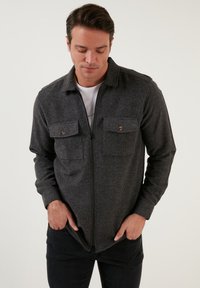 Szürke, cipzáras dzseki texturált anyagból, két gombos mellzsebbel és galléros nyakkal. Slim fit, hosszú ujjú, laza stílus.