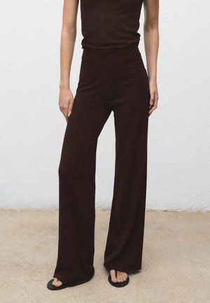 Brown, wide-leg pants made of soft fabric, paired with a fitted, matching brown top. Model wears simple black flip-flops.