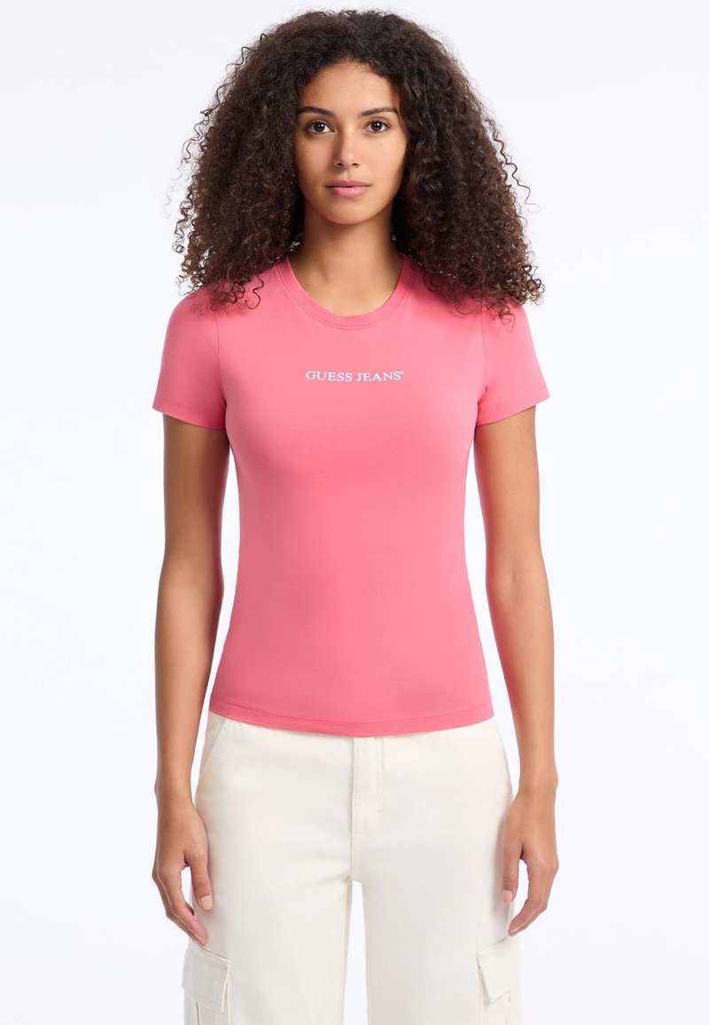 Rožinė, prigludusi marškinėlių su elastine medžiaga, turinti apvalią iškirptę ir trumpas rankoves. Priekyje yra baltas "GUESS JEANS" logotipas.