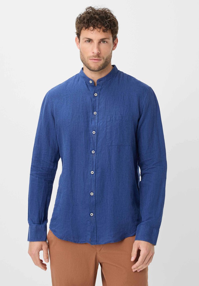 Camicia blu in lino a maniche lunghe con colletto a band, bottoni frontali e taschino sul petto. Caratterizzata da un tessuto testurizzato e una vestibilità sartoriale.