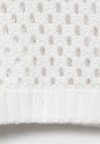 Weißer gestrickter Stoff mit einem offenen, netzartigen Muster, das verlängerte Löcher aufweist, und einer gerippten, soliden Textur am unteren Rand.