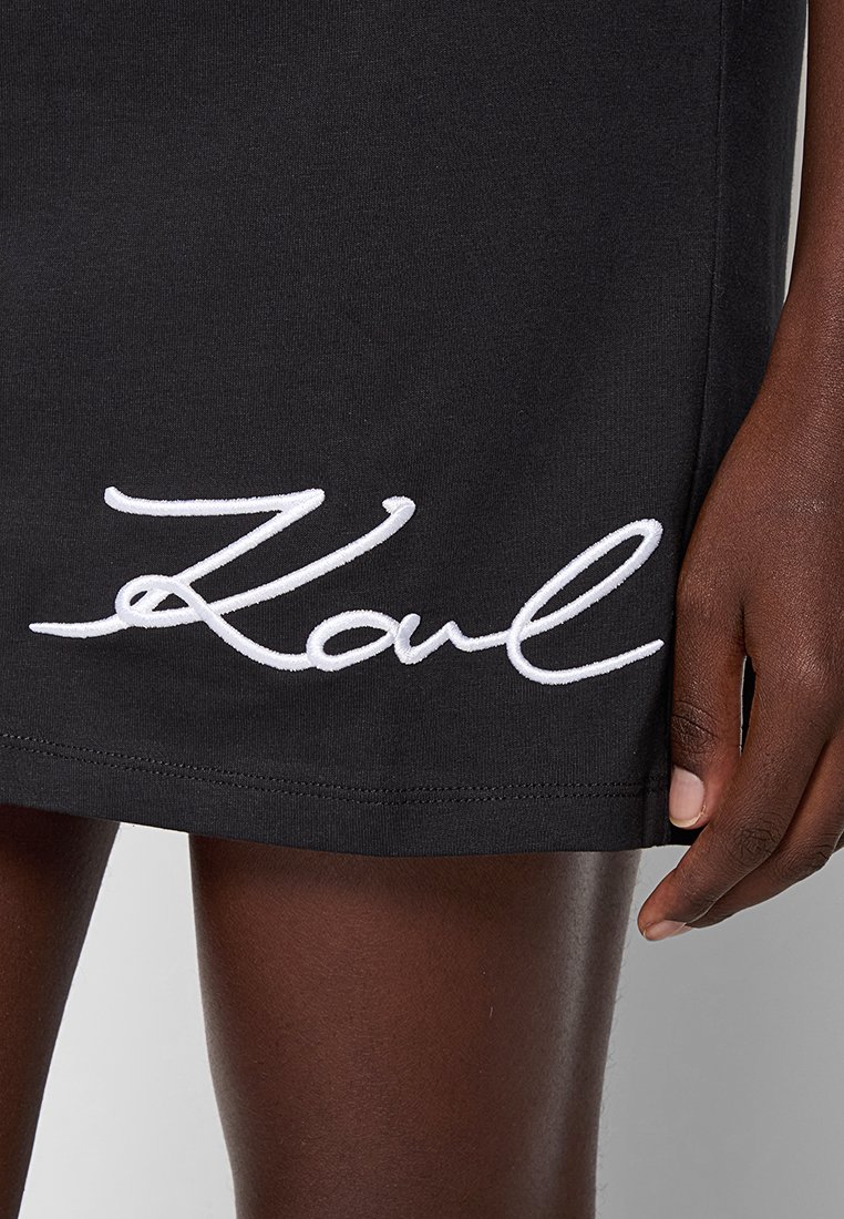 Robe en coton noir avec un texte brodé en blanc "Karl" au bas. Texture lisse avec une silhouette ajustée.