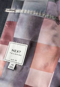 Taga slim-fit koszuli od NEXT z gładkiego materiału, na którym znajdują się duże pastelowe kwadraty w odcieniach różu, fioletu i szarości. Metka wszyta na dole.