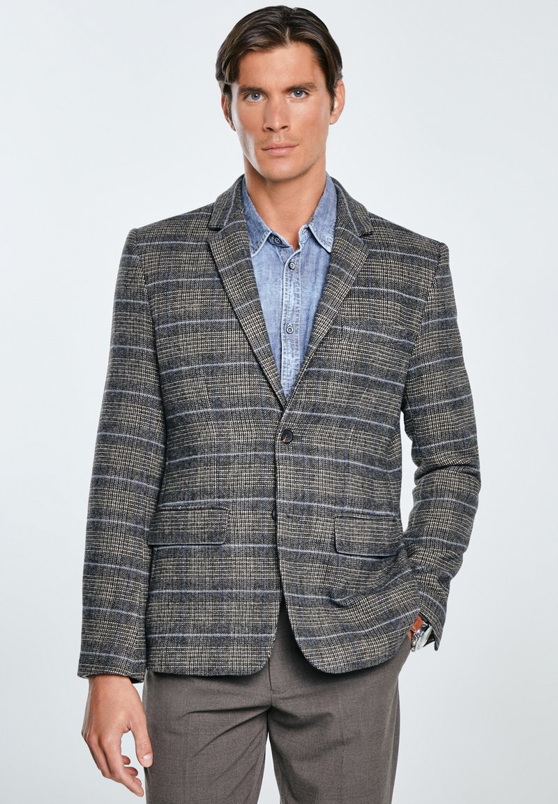 Karierter Blazer in Grau- und Blautönen, mit strukturiertem Stoff,reversierten Klappen und zwei vorderen Taschen über einem Jeanshemd.