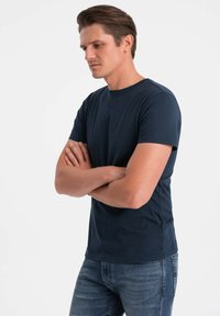 Námorně modré bavlněné tričko s kulatým výstřihem, krátkými rukávy a jednoduchým střihem, v kombinaci s tmavými džíny.