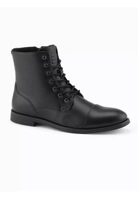 Botas de tobillo de cuero negro con acabado texturizado, que cuentan con ojales de metal, diseño de cordones, punta redondeada y suela plana de goma.