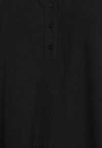 Camicia nera con bottoni, realizzata in un tessuto testurizzato e con una placca che presenta quattro bottoni. Design semplice, senza pattern né dettagli aggiuntivi.
