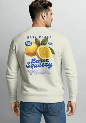 Helle beige Sweatshirt mit einem Zitronen-Graphic und fettem blauen Text auf der Rückseite. Enthält grüne Blätter und ein Design im Vintage-Stil.
