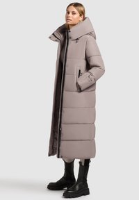 Lange, puffy jas in licht taupe, met een hoge kraag, ritssluiting en twee zijzakken. De stof lijkt glad met een gestructureerd ontwerp.