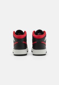 Black leather high-top sneakers with red accents, white midsole, and textured rubber outsole. Features logo detail on the heel.