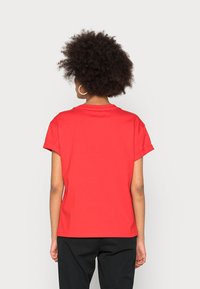 Red short-sleeve t-shirt made of cotton. Features a round neckline and relaxed fit. Visible stitching detail along sleeves and hem.