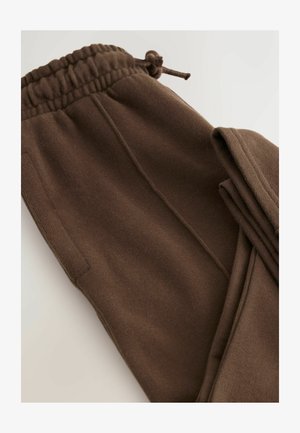 Braune Jogginghosen aus weichem Stoff. Mit einem elastischen Bund und Kordelzug, seitlichen Taschen und einer glatten Textur.