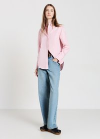 Light pink button-up shirt with long sleeves, paired with light blue wide-leg jeans and black wooden-heeled clogs.