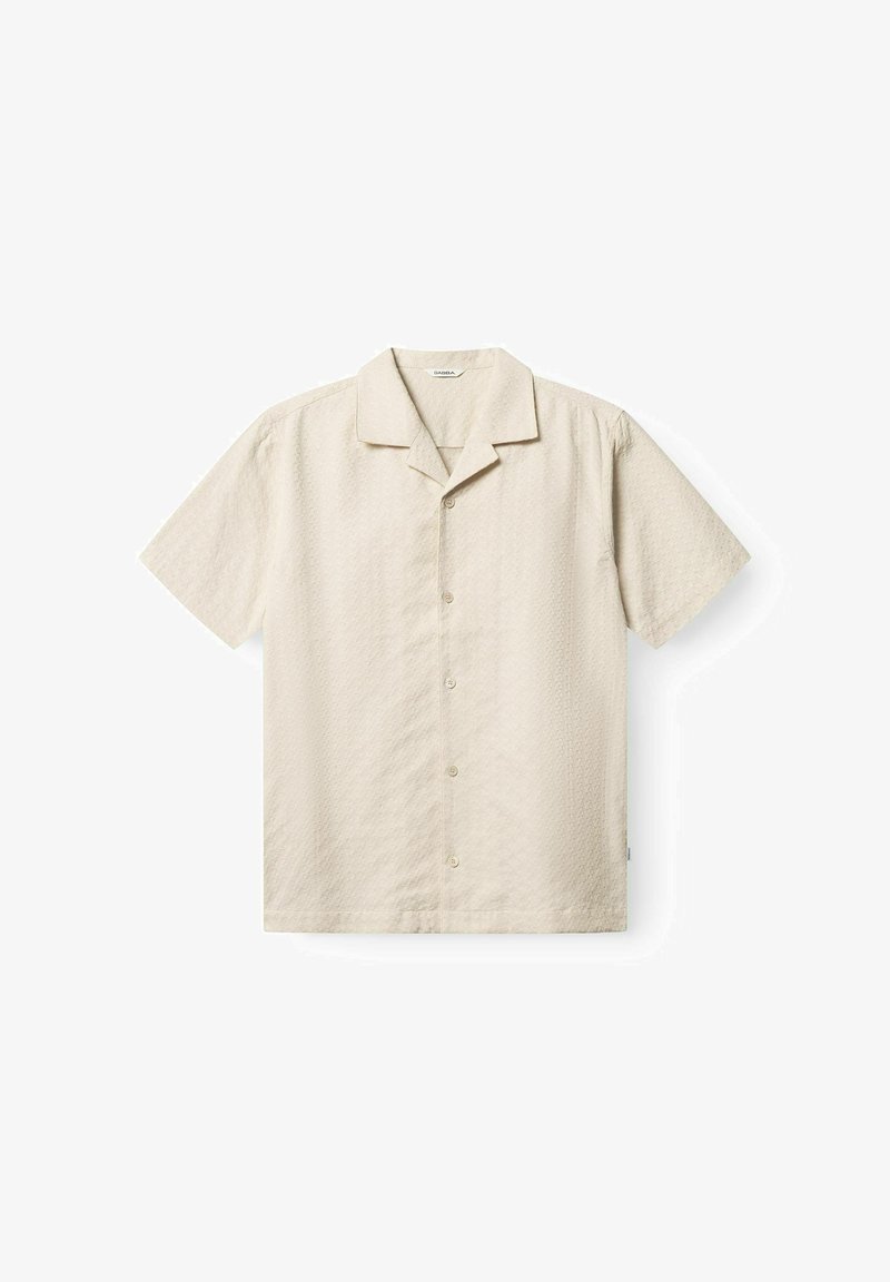 Beež lühikeste varrukatega särk nööpidega, laagrikrae ja peene tekstuuriga mustriga, sirgelt valgele taustale laotatult.