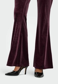 Bløde, dyb burgunderfarvede udsvingede bukser kombineret med blanke, sorte laklæder høje hæle med åben hæl og spids tå.