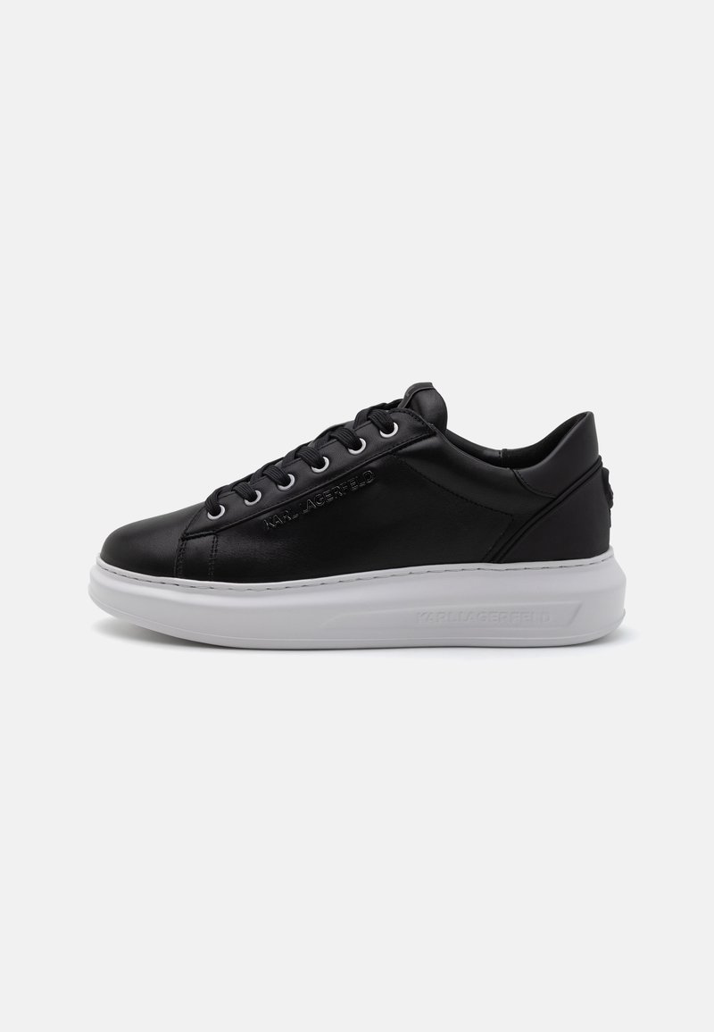 Black leather sneakers with a white sole, rounded toe, and lace-up design. Features embossed logo and smooth texture.