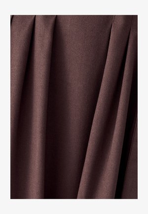 Tessuto marrone scuro con morbide pieghe e una trama intrecciata visibile, appeso verticalmente in delicate drappe.