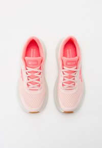 Sneakers Skechers con una toma superiore in rete di un rosa chiaro, punta rinforzata, design con lacci e suola ammortizzata con un fondo grigio chiaro texturizzato.