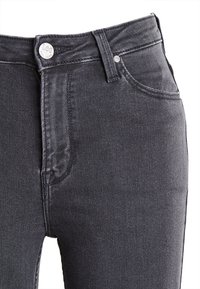 Czarne dżinsy z wysokim stanem, klasycznym pięciopocketowym krojem i metalowym zapięciem. Teksturowana tkanina o niewielkiej elastyczności.
