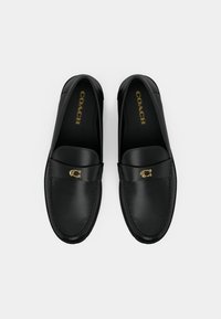 Mustat nahka loaferit pyöreällä kärjellä, kultainen logo koristetta nauhassa ja sileä pinta. Sisällä on kultainen brändikirjoitus.