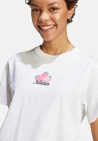 Vit bomull t-shirt med en rosa jordgubbsgrafik och "Adidas" text i svart, kort ärm och rundad halsringning.
