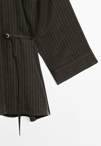 Brown pinstriped shirt featuring a tied waist and wide sleeves, laid flat against a white background.