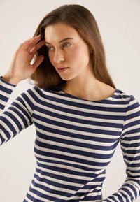 Long-sleeve top in navy and white stripes, featuring a boat neckline and soft, stretchy cotton fabric. Close-fitting design.