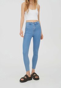 Vaaleansiniset korkeavyötäröiset skinny-farkut, joissa on viisi taskua ja haalistunut pinta. Yhdistetty mustiin platform-sandaaleihin.