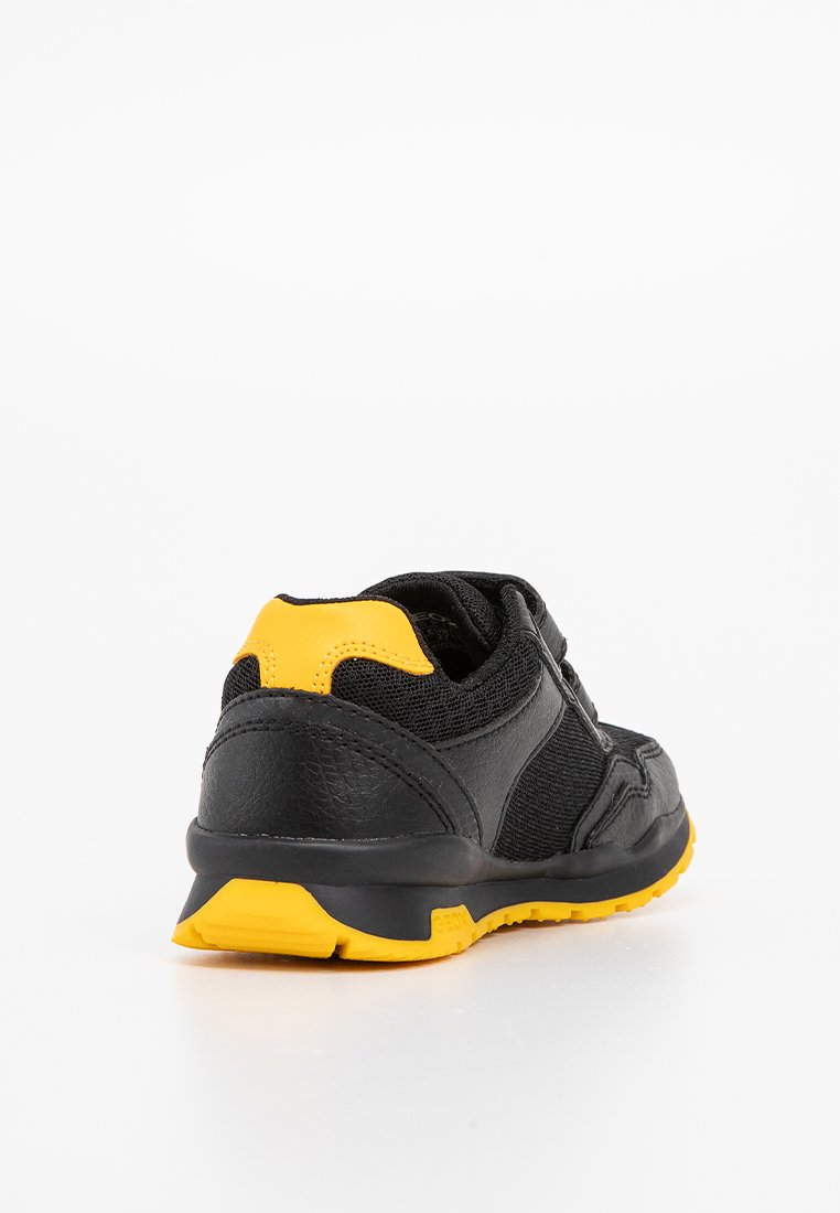 Chaussure de sport noire avec des accents jaunes. Présente un dessus en synthétique texturé et des panneaux en maille, une semelle rembourrée et un design de talon courbé.