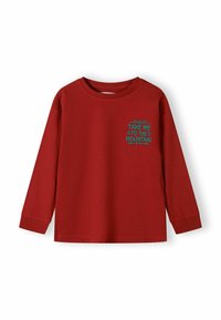 Sarkana krekls ar garām piedurknēm un tirkīza kalnu grafiku, uz kreisās krūtis ir uzraksts "Aizved mani pie kalna".