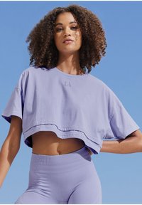 Purple cropped t-shirt with a round neck and short sleeves, featuring a small "LA" logo on the front; paired with high-waisted purple leggings.