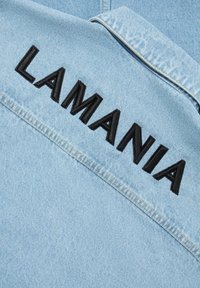 Hele sinine denim jakker, mille seljal ülaservas on must tikitud tekst "LAMANIA". Omab klassikalist krae ja eristuvat õmblust.