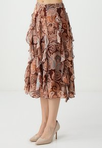 Bruine paisley-print rok met gerimpelde lagen, in tinten perzik, crème en blauw. Draag met beige hoge hakken.