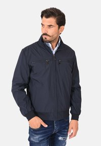 Giubbotto bomber blu navy realizzato in tessuto leggero, con colletto alto, due tasche sul petto con zip e polsini a costine.