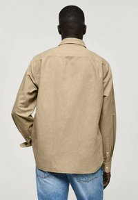 Khaki langærmet skjorte med knapmanchetter, afslappet pasform og rygkirke detalje, lavet af et tekstureret stof. Sammen med denim.