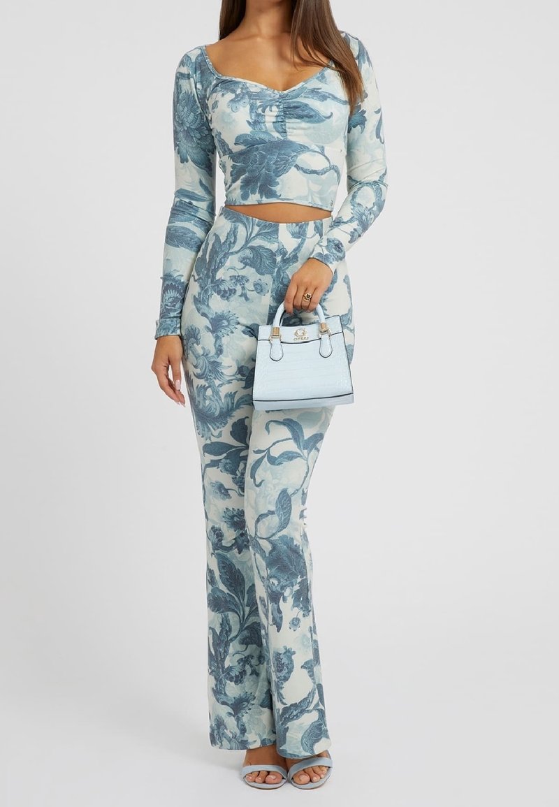 Dvoudílný outfit obsahující dlouhý rukáv crop top a rozšířené kalhoty s modrým květinovým potiskem na světlém pozadí. Doplňený světle modrou kabelkou.