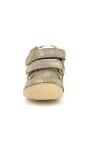 Zapato de velcro con una suela beige suave; la parte superior presenta una tela texturizada e iridiscente en tonos de verde apagado y beige. Diseño de punta redondeada.