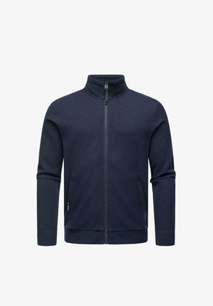 Marineblaue Zip-Jacke mit hohem Kragen, strukturiertem Stoff, zwei seitlichen Taschen und einem kleinen Logosticker auf der linken Seite.