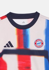 FC Bayern München-drakten har et grafisk design med røde, blå og rosa mønstre. Den har en rund marineblå krage og en svart Adidas-logo.