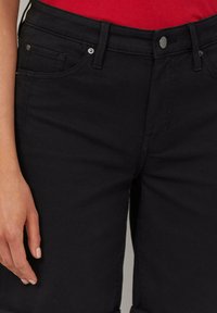 Shorts en denim noir au design ajusté, présentant une texture lisse, des poches avant et des accents en métal.